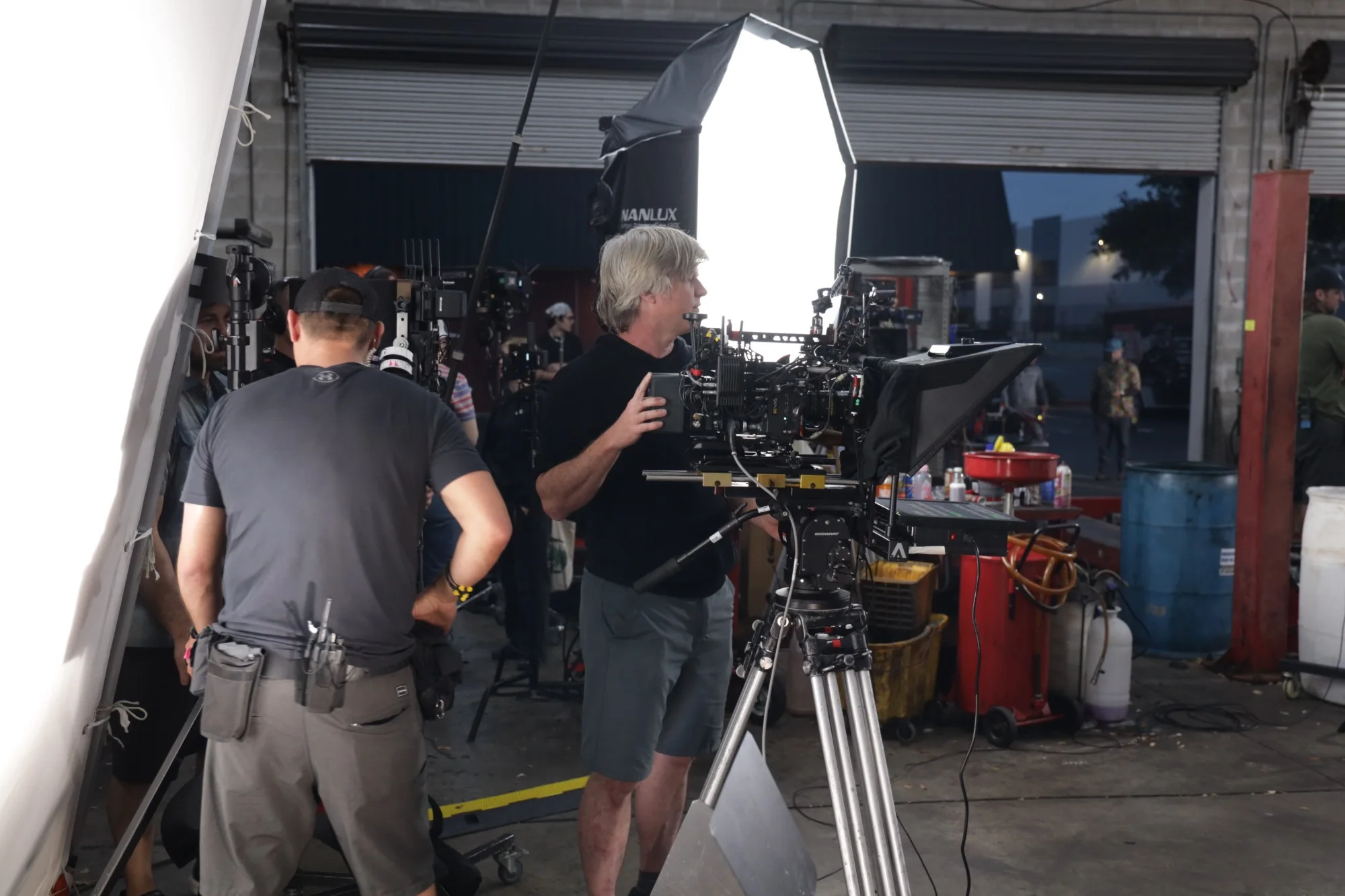 Camera operators and crew beside a lit camera rig inside a garage