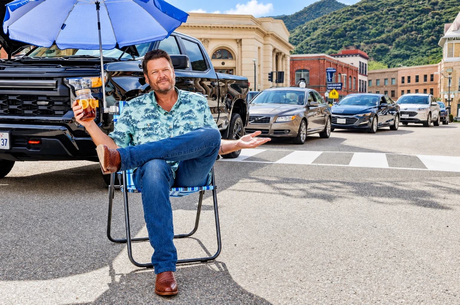 A performer in a lawn chair beside a pickup truck on a small-town main street, holding a jar of iced tea