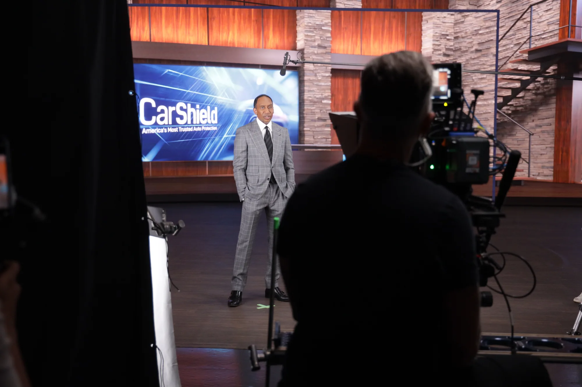 Camera operator in the foreground filming a performer in a studio